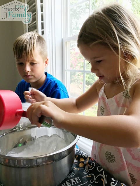 L'enfant ajoute les ingrédients dans le bol en métal.
