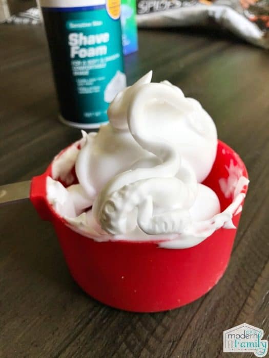 Une tasse de crème à raser dans une tasse à mesurer rouge.