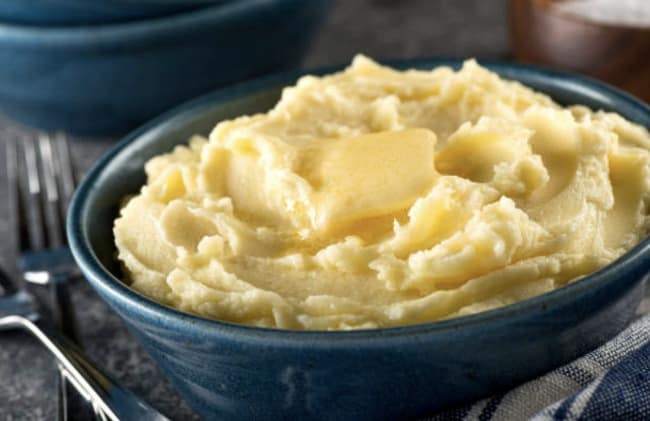 Une assiette de purée de pommes de terre avec du beurre sur le dessus.
